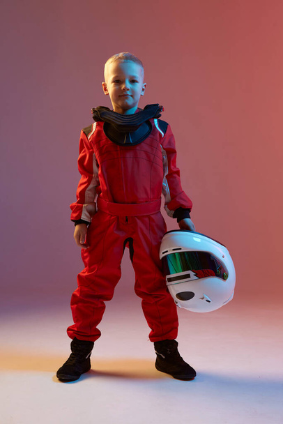 Cool boy child racer with helmet, standing in neon light. Kart racing school poster. Competition announcement - Foto, Imagen
