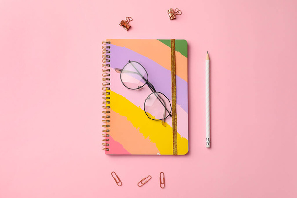 Stylish notebook with pencil and eyeglasses on color background - Photo, Image