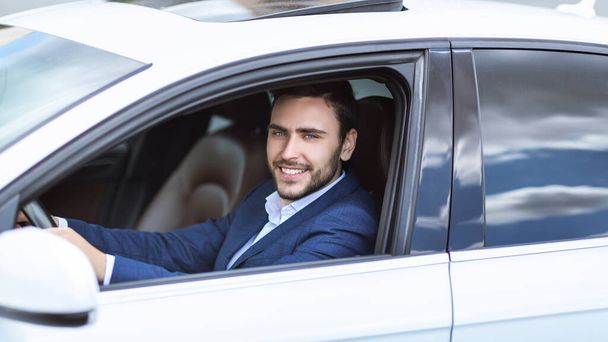 Happy CEO κάθεται σε οδηγούς κάθισμα του αυτοκινήτου του, πηγαίνει να εργαστεί σε μεγάλη πόλη - Φωτογραφία, εικόνα
