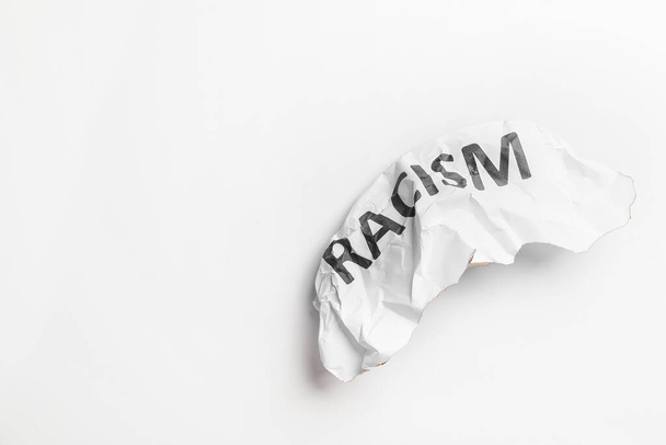 Θρυμματισμένο χαρτί με κείμενο RACISM σε λευκό φόντο - Φωτογραφία, εικόνα