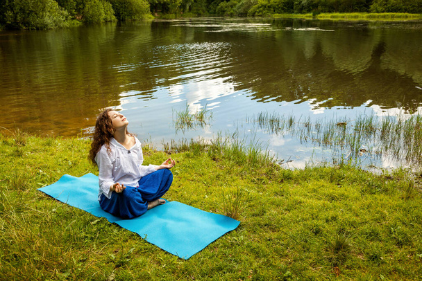 The girl practices yoga by the lake. - Φωτογραφία, εικόνα