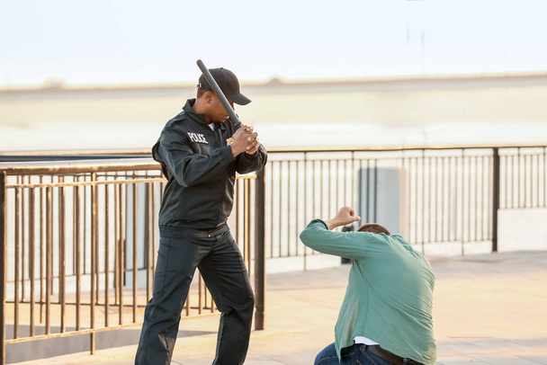 Agressieve Afro-Amerikaanse politieagent mishandeld man buiten - Foto, afbeelding