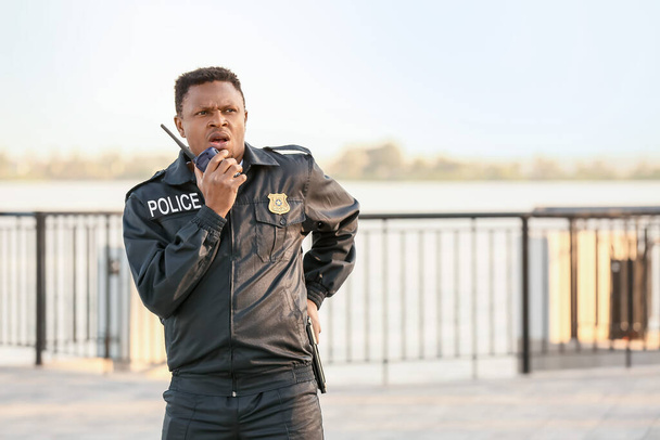 Αφροαμερικανός αστυνομικός με αμφίδρομο ραδιόφωνο στην ύπαιθρο - Φωτογραφία, εικόνα