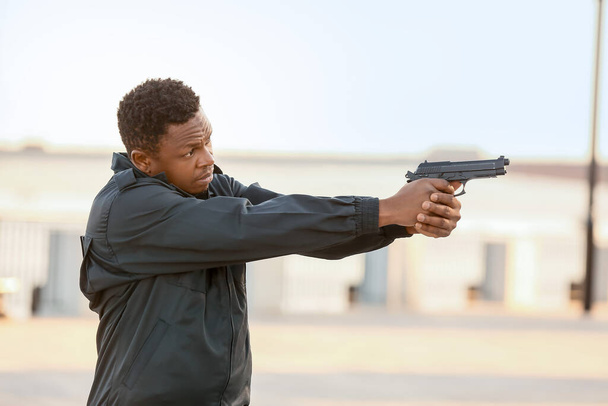 屋外で銃を持つ積極的なアフリカ系アメリカ人警察官 - 写真・画像