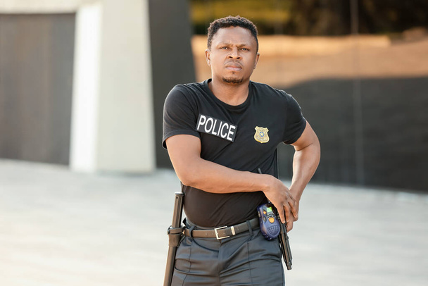 Afrikai-amerikai rendőrtiszt fegyverrel a szabadban - Fotó, kép