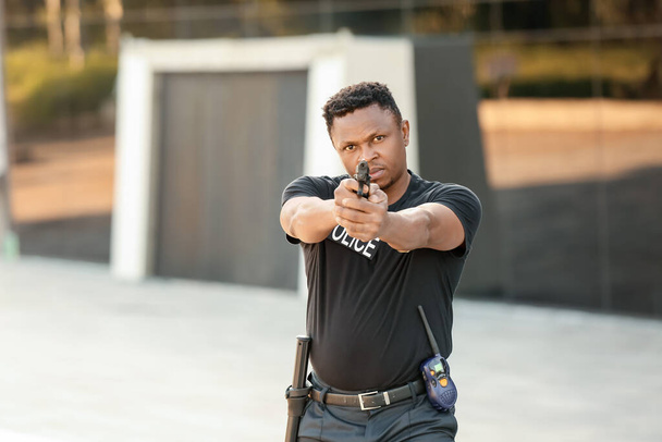Aggressive African-American police officer with gun outdoors - Photo, Image