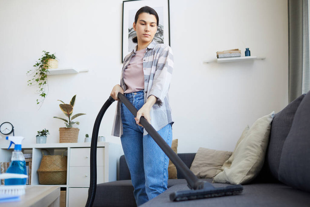 Woman vacuuming the sofa - Photo, Image