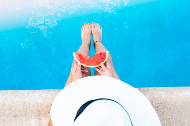 Girl holding watermelon in the blue pool, top view Summer vacation is idyllic. - Фото, изображение