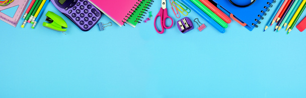 School supplies top border. Above view over a blue paper banner background with copy space. Back to school concept. - Fotó, kép