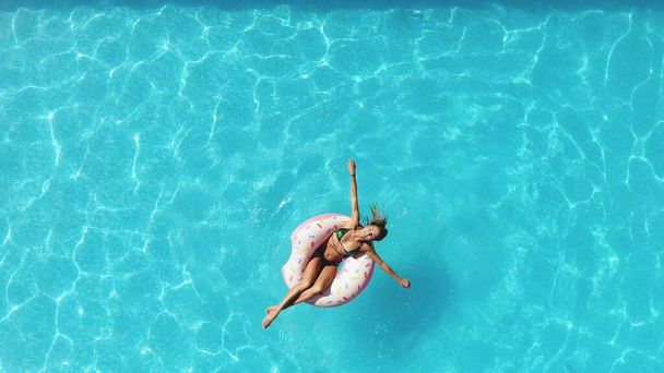 Chica en la piscina nada en una dona inflable de color rosa
 - Foto, imagen