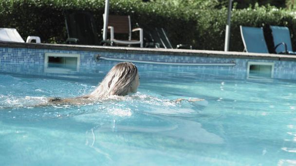 Вид збоку сексуальна жінка спускається в басейн і плаває
 - Фото, зображення
