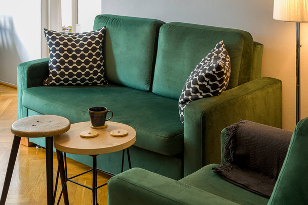 Intérieur - canapé et fauteuil vert foncé, à côté de la lampe, table et tabouret, sol en bois sur le sol - Photo, image