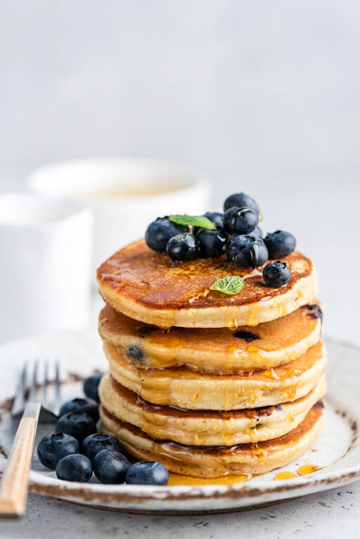Blueberry pancakes with honey on plate. Stack of fluffy pancakes. Tasty sweet breakfast food - Фото, изображение