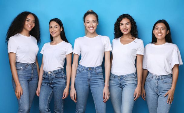 Cinco chicas modelo sonriendo a la cámara posando sobre fondo azul
 - Foto, Imagen