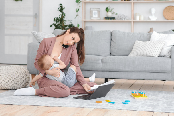 Young Mom Working On Laptop And Talking On Cellpone While Breastfeeding Baby - Φωτογραφία, εικόνα