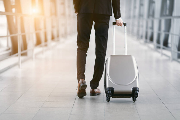 Városi üzletember sétál a repülőtéren bőrönddel - Fotó, kép