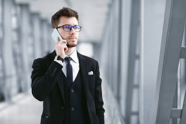 Serious business man talking on smartphone wearing specs - Photo, Image