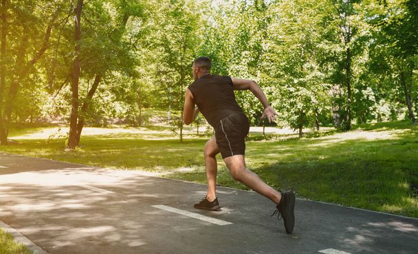 Black sprinter running at park on sunny morning, free space - Фото, изображение