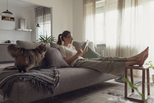 Woman relaxing on the sofa and connecting with her tablet in the living room - Photo, image