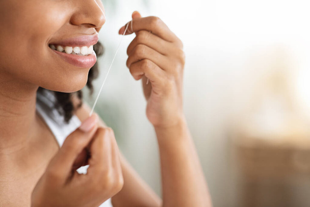 Fogápolási rutin. Mosolygó fekete nő tökéletes fogak segítségével fogselyem - Fotó, kép