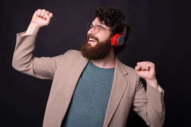 Photo of happy man in casual listening music at wireless headphones - Foto, afbeelding