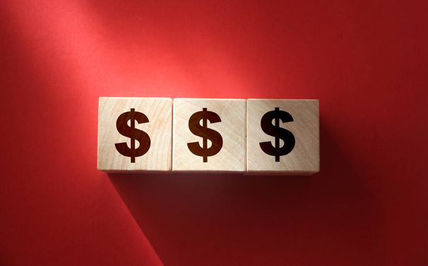 Holzblöcke mit Dollarzeichen auf rotem Hintergrund. Geschäftskonzept von Reichtum oder Gewinn - Foto, Bild