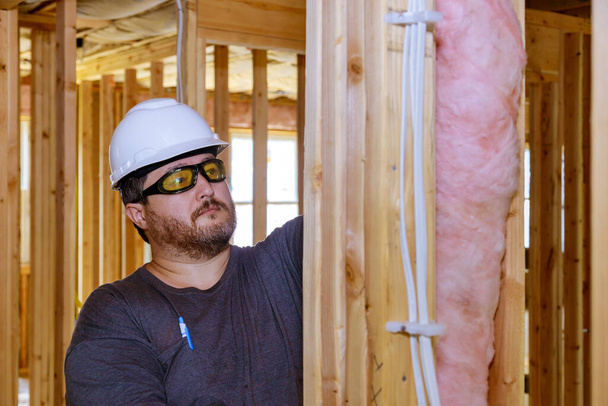 Robotnik budowlany termoizolacyjna warstwa izolacyjna pod domem z wełną szklaną miękka ostrość - Zdjęcie, obraz
