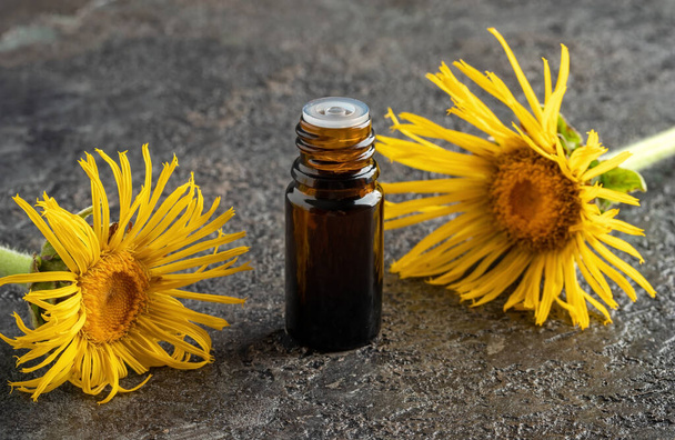 Una botella gotero de aceite esencial de páncreas con flores de helenio Inula
 - Foto, Imagen
