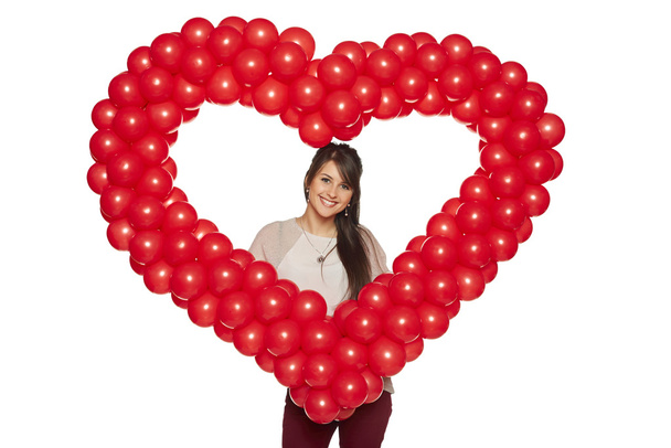 Smiling woman holding red balloon heart - Фото, зображення