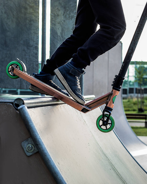 Adolescente menino monta em chute scooter no skatepark ao ar livre. Verão competição esportiva extrema fora. Pés de adolescente do sexo masculino montando em concurso. Aprenda a fazer truques
 - Foto, Imagem