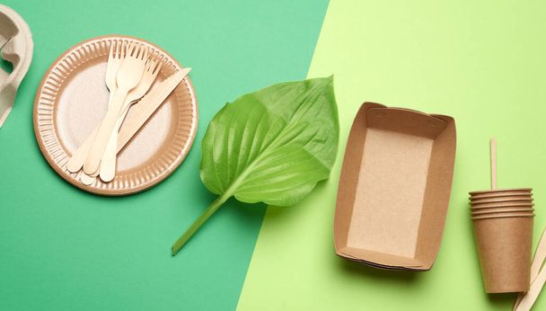 одноразовий паперовий посуд з коричневого ремесла та перероблених матеріалів на зеленому фоні, концепція пластикової відмови, нульові відходи
  - Фото, зображення