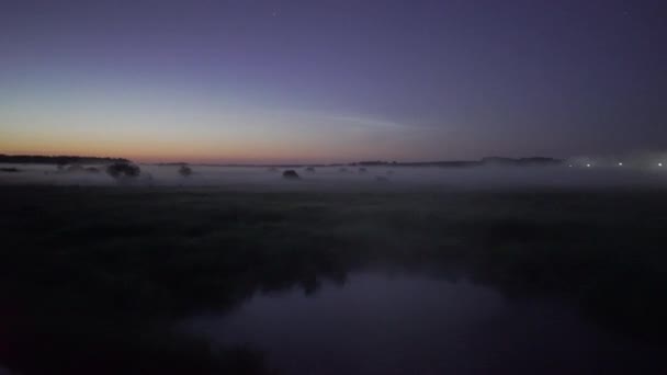 霧は夜の満月を背景に草や湖の上に横たわる - 映像、動画