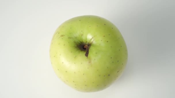 Manzana verde madura sobre un fondo blanco de cerca. Tallo seco. Rotación lenta. Vista desde arriba. Ingredientes nutritivos
 - Metraje, vídeo