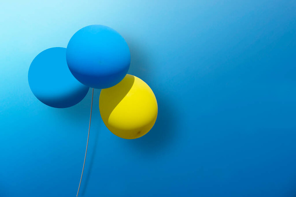 Sparse 3d design met blauwe en gele ballonnen op blauwe achtergrond. Kopieerruimte, kan worden gebruikt als wenskaart. - Foto, afbeelding