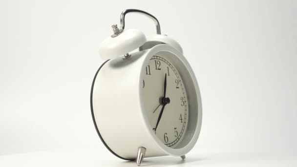 White classic analog alarm clock on a white background. Slow rotation. Metal bells. Countdown and time concept - Кадри, відео