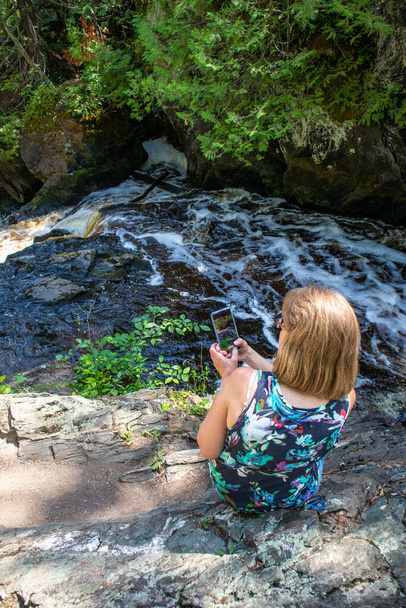 Lady taking a picture of a river with her smartphone, Vertical - Photo, Image