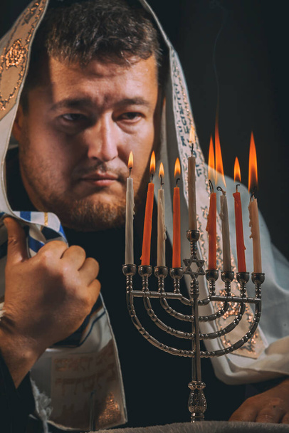 Jewish man with beard lighting the candles in prayer of a Hanukkah menorah lights candles - Photo, Image
