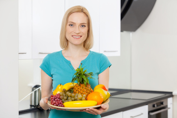Woman holding a plate with fruits - Foto, Imagem