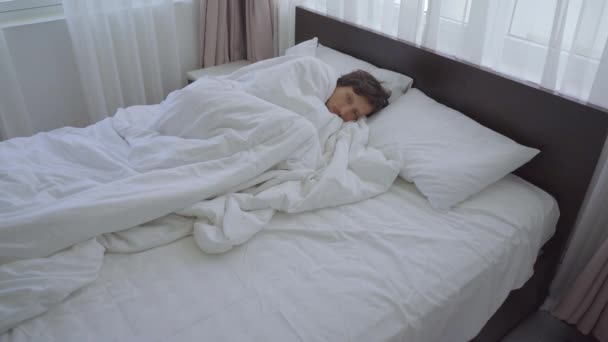 A man feels cold in a bed. he is trying to warm up under the blanket. fever concept - Metraje, vídeo