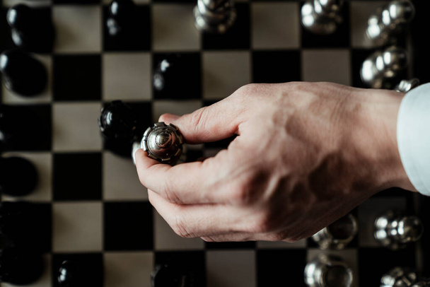 Piezas de ajedrez de madera negra colocadas en tablero de ajedrez. Figuras de ajedrez de madera, vista superior. Juego para el desarrollo cognitivo. Mano moviendo ajedrez rey. Manera de mejorar su estado físico cerebral
. - Foto, imagen