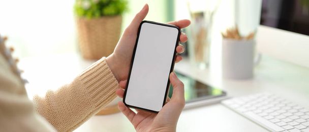 Zblízka pohled na ženské ruce drží maket-up smartphone zobrazit informace, zatímco stojí u pracovního stolu - Fotografie, Obrázek