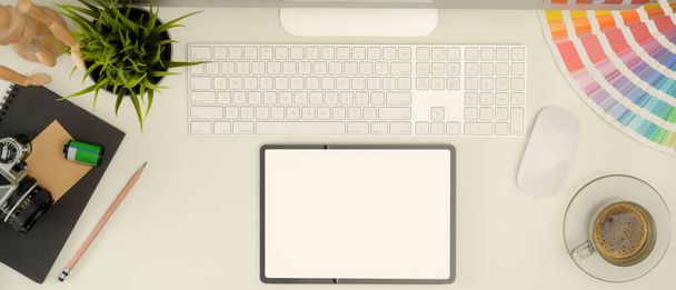 Ofis masasında bilgisayar aygıtı, renk örneği, kırtasiye malzemesi, kamera ve kahve fincanı olan dijital tabletin üst görünümü - Fotoğraf, Görsel