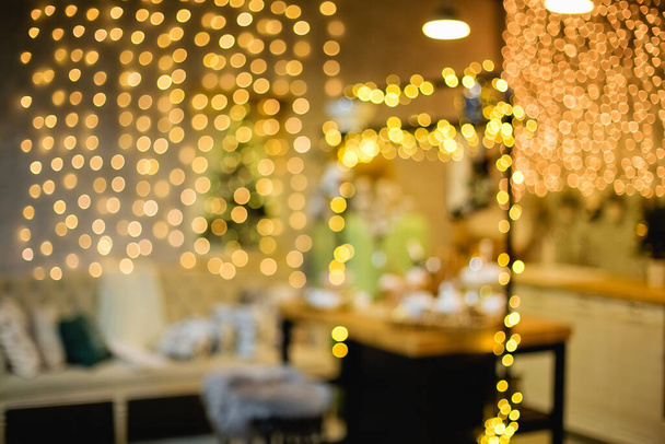 Blurred Christmas background with Christmas tree and lights. A lot of glare and blurred bokeh of gold color. - Photo, Image