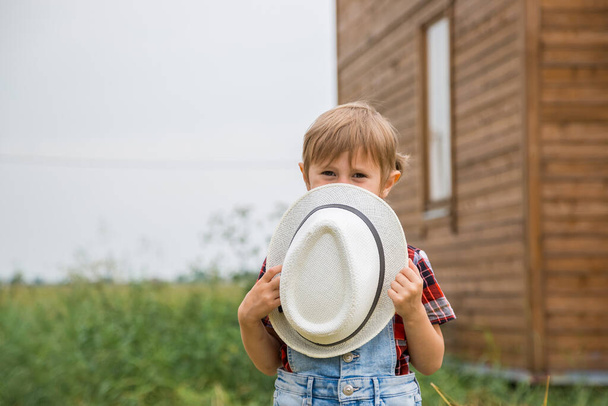 Cute little girl in a cowboy hat,dressed in a denim shorts and red white shirt  - Valokuva, kuva