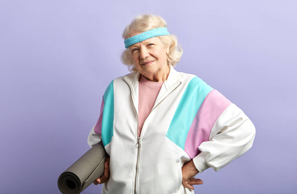 Happy elderly woman holding a yoga mat - Foto, Imagem