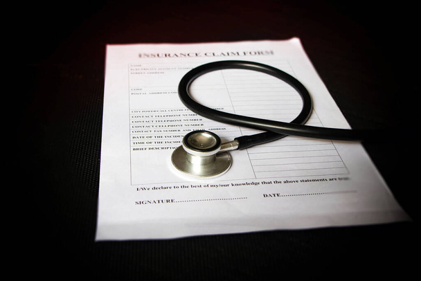 Head of Stethoscope put on blurred Insurance claim form,Lens flare effect,blurry light around - Photo, Image