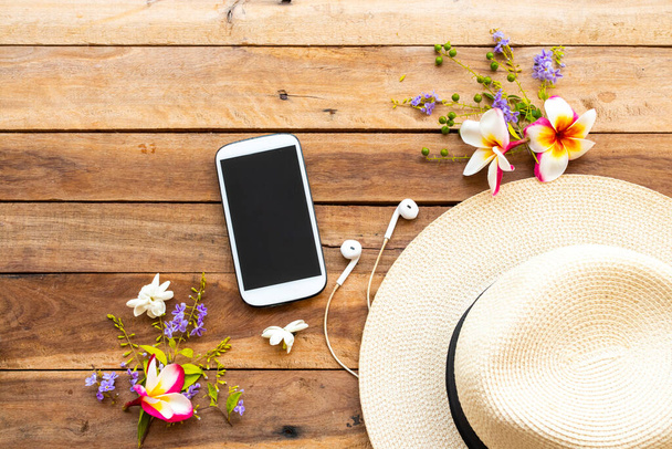 mobile phone ,earphone ,hat and flowers of lifestyle woman relax  arrangement flat lay style on background wooden - Foto, afbeelding