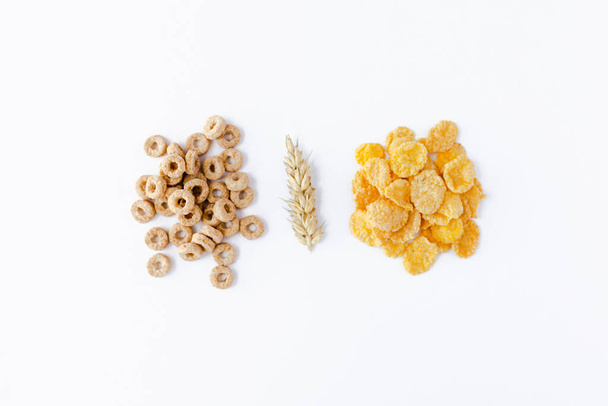 Handful of cheerios, wheat germ and cornflakes on white background. Breakfast cereals. - Photo, image
