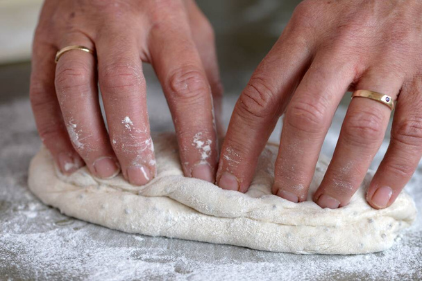  Hornear en casa: panaderos manos moldeando baguettes en mesa de madera
 - Foto, imagen