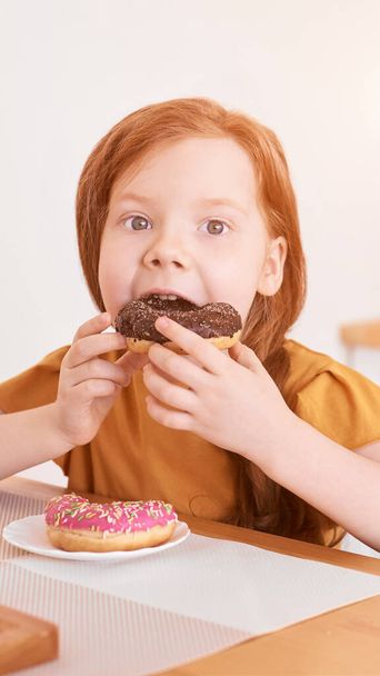 Little girl eating round doughnut. Sweet desert. Unhealthy food - 写真・画像
